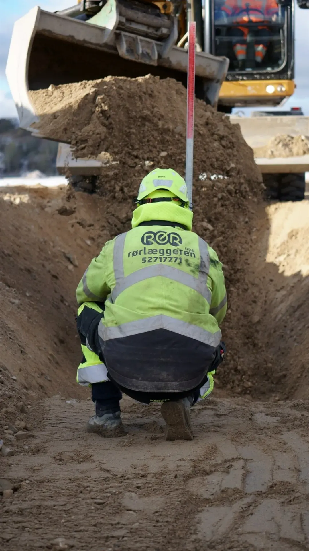 Rørlægger i arbejde med jordarbejde og rørinstallationer.