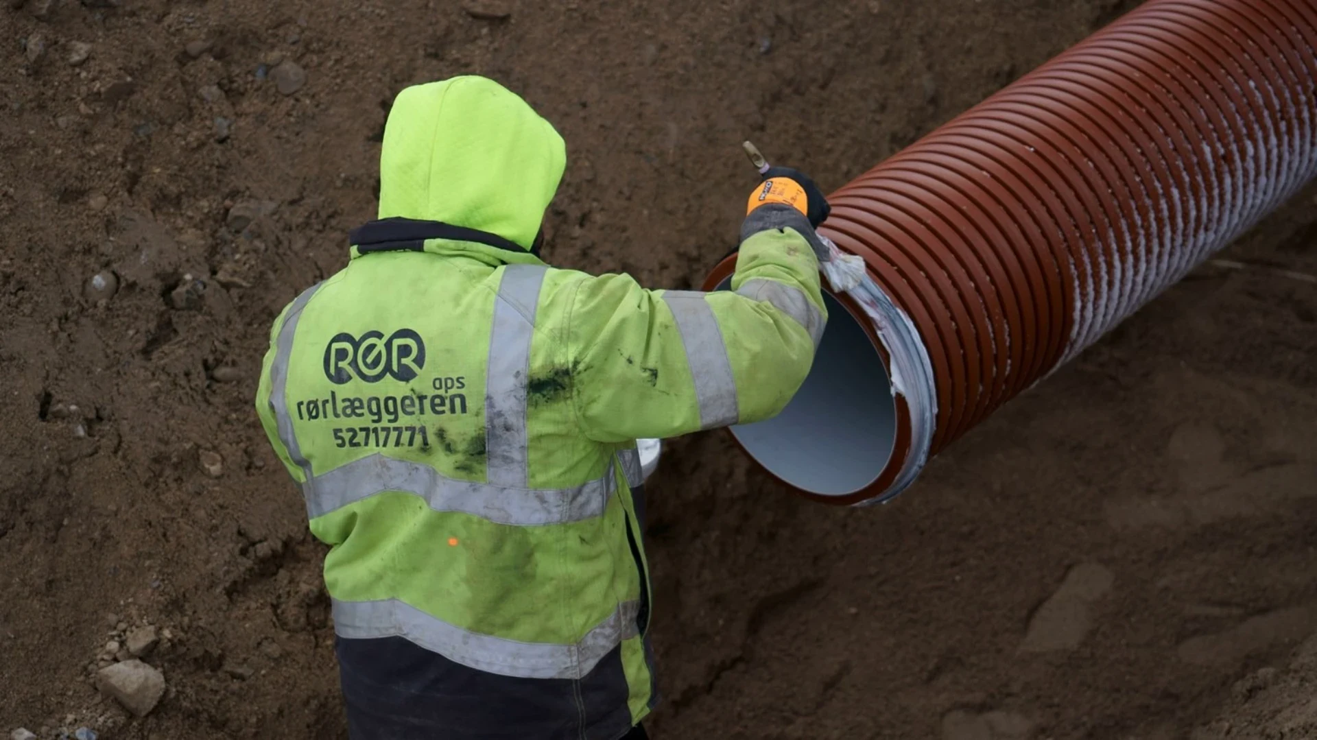 Rørlægger arbejder med jord- og rørinstallationer i byggeprojekt.